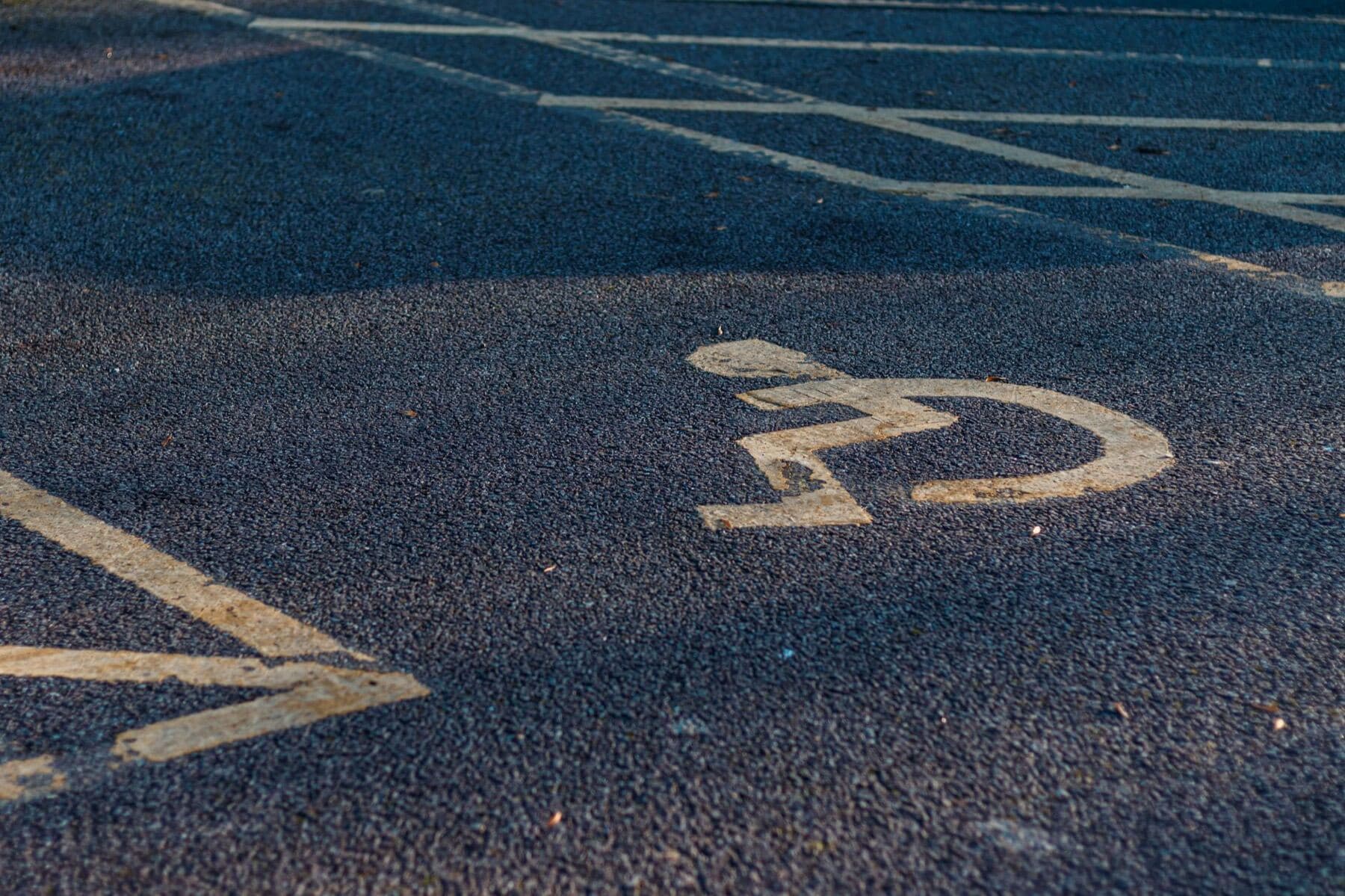 A yellow accessible-stall symbol painted on asphalt.
