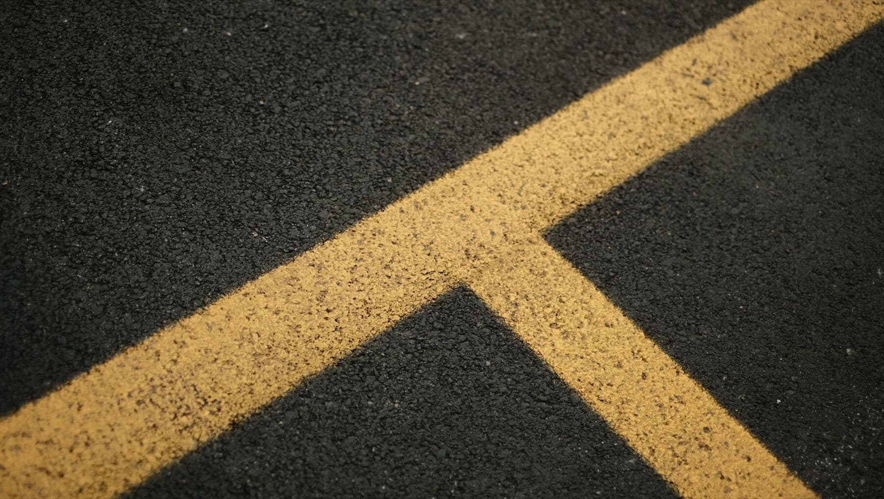 Bright yellow lines painted across a dark asphalt surface.