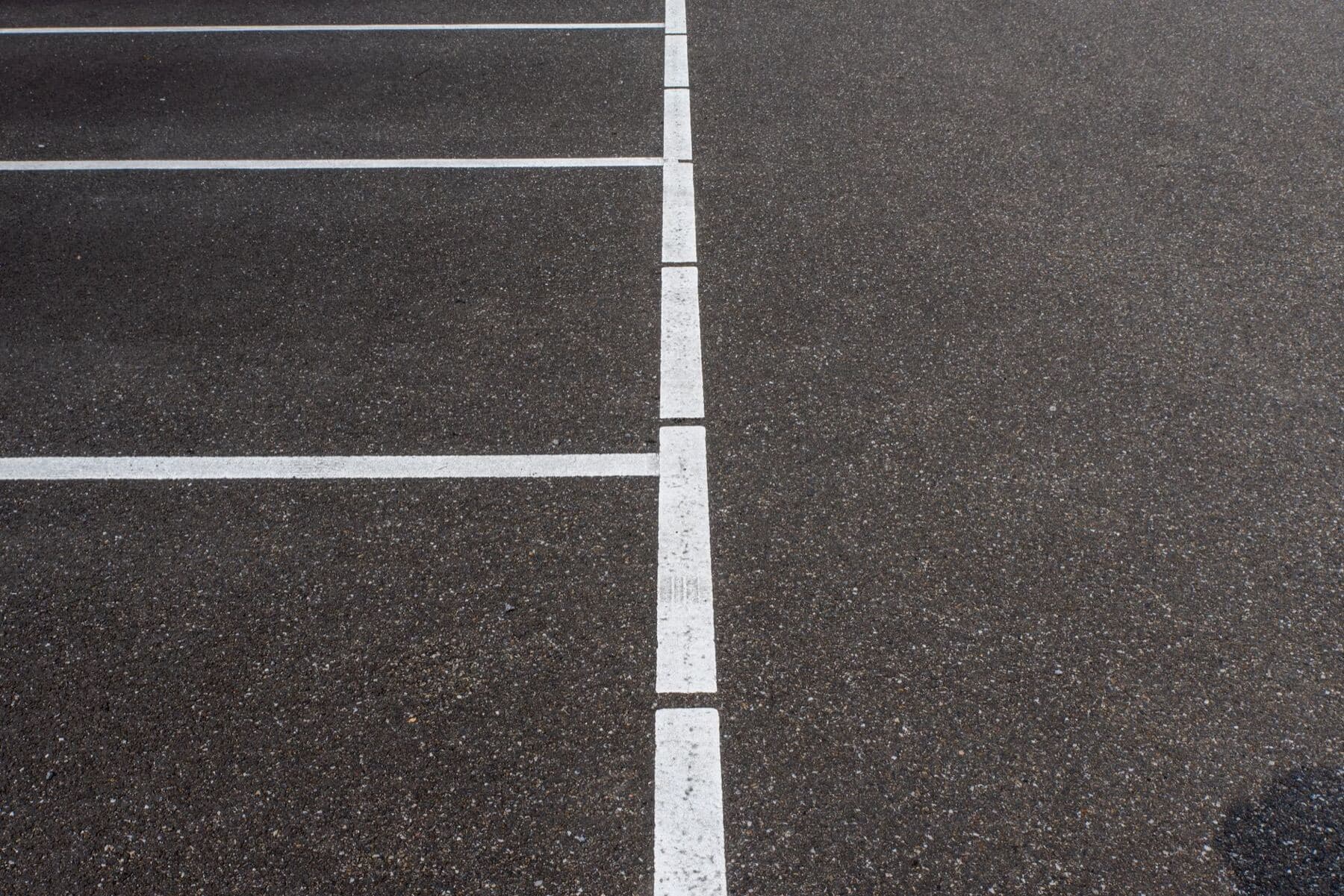 An empty asphalt parking lot with crisp white stall lines.
